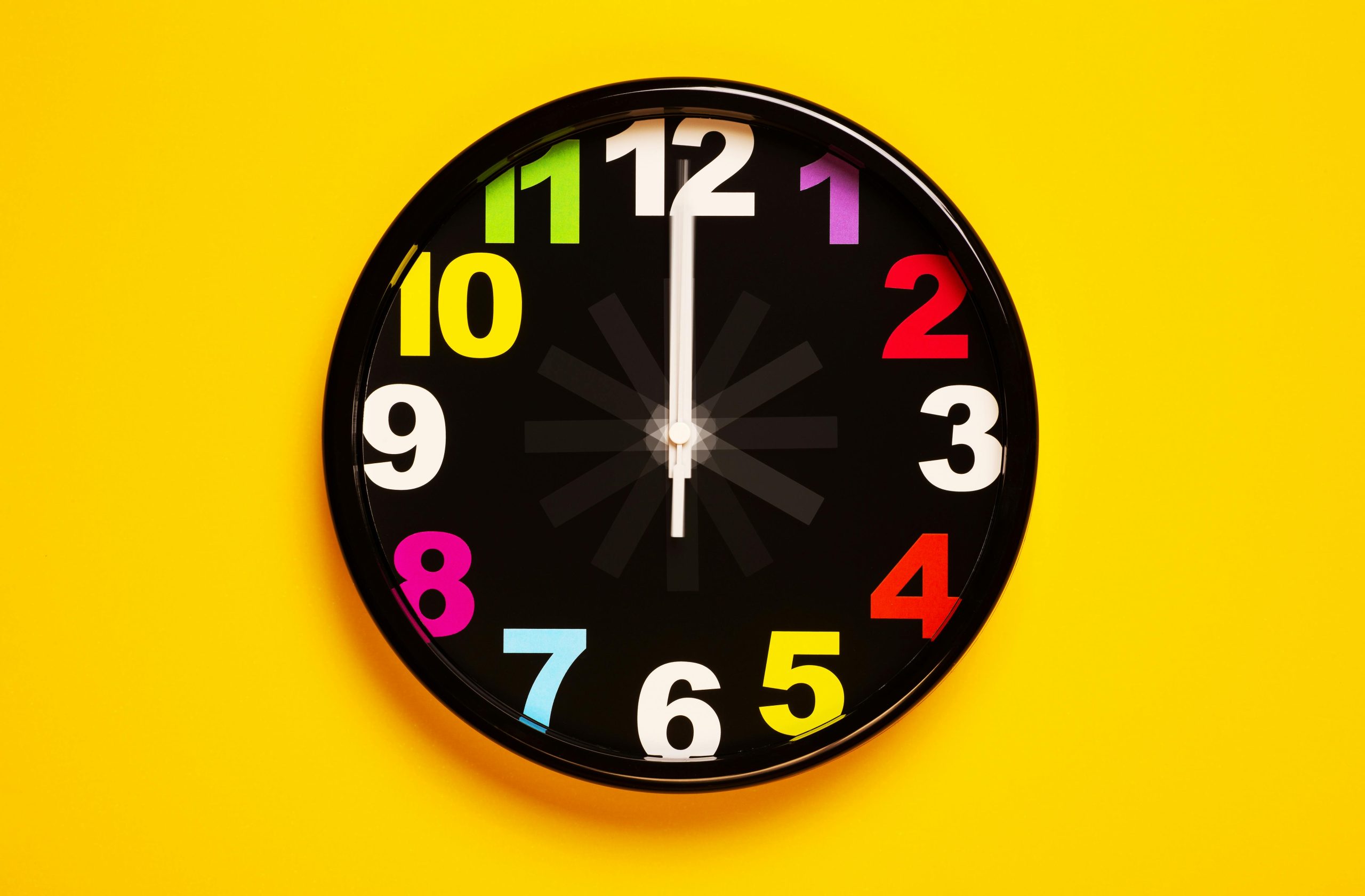 课后辅导 Vibrant wall clock with colorful numbers on a bright yellow background, emphasizing modern decor.